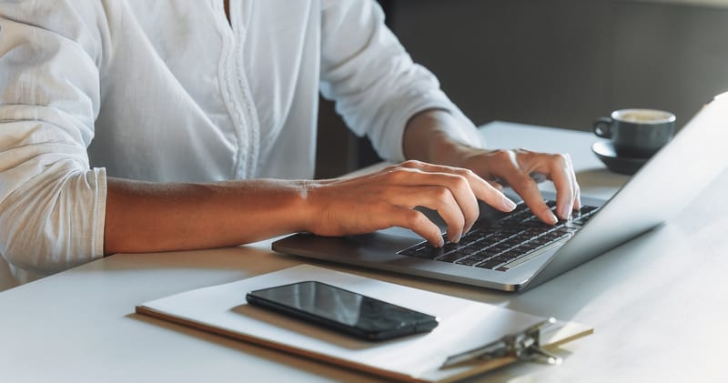 Woman reviewing resumes on laptop at desk