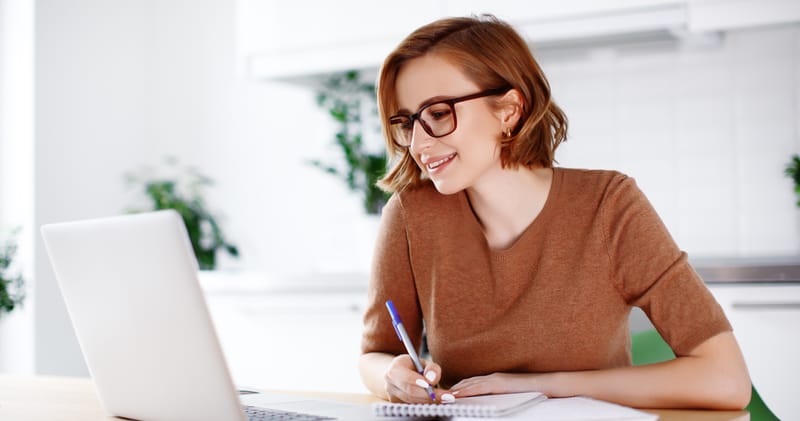 Young woman taking notes in front of a laptop